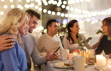 Image showing happy couple with smartphone at family tea party