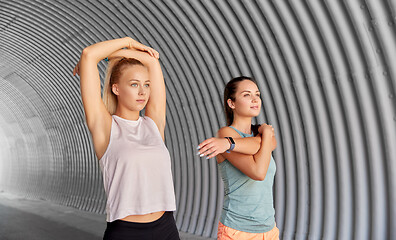 Image showing women with fitness trackers stretching outdoors