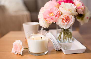Image showing burning candle and flower bunch on table at home