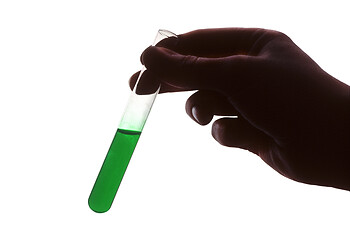 Image showing Hand holding test tube of green liquid against white