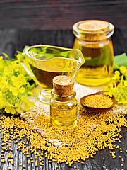 Image showing Oil mustard in two jars and gravy boat on dark wooden board