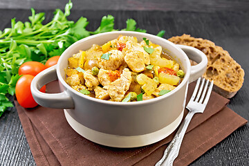 Image showing Chicken with vegetables and peas in saucepan on dark board