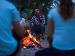 Image showing young friends relaxing around campfire