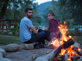 Image showing couple sitting around the campfire at evening