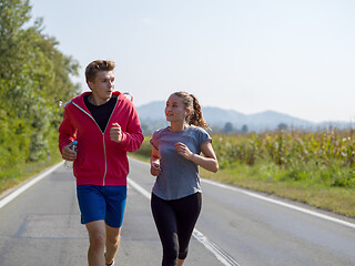 Image showing young couple jogging along a country road