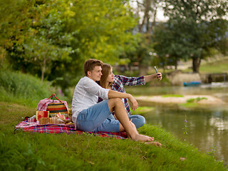 Image showing Couple taking a selfie by mobile phone while enjoying picnic tim