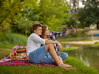 Image showing Couple taking a selfie by mobile phone while enjoying picnic tim