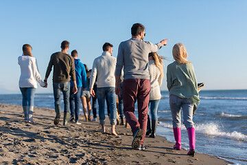 Image showing Group of friends running on beach during autumn day