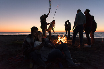 Image showing Couple enjoying bonfire with friends on beach