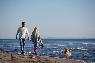 Image showing couple with dog having fun on beach on autmun day