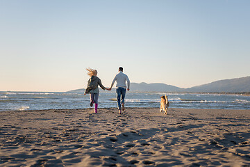 Image showing couple with dog having fun on beach on autmun day