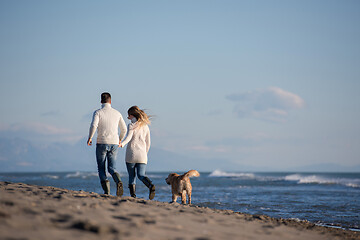 Image showing couple with dog having fun on beach on autmun day