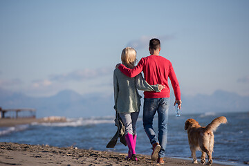 Image showing couple with dog having fun on beach on autmun day