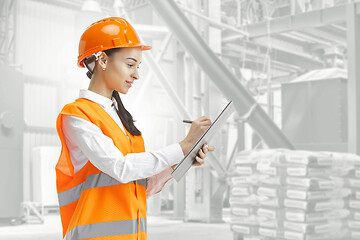 Image showing Destroying gender stereotypes. Female builder standing against industrial background