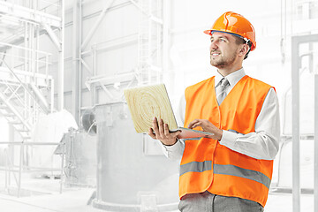 Image showing The builder in orange helmet against industrial background