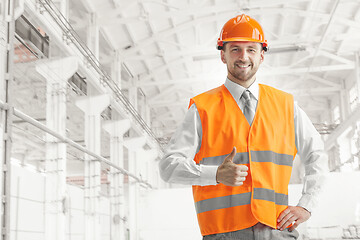 Image showing The builder in orange helmet against industrial background