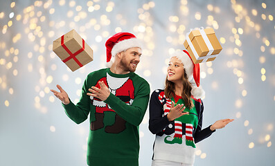 Image showing happy couple in ugly sweaters with christmas gifts