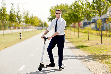 Image showing young businessman riding electric scooter in city