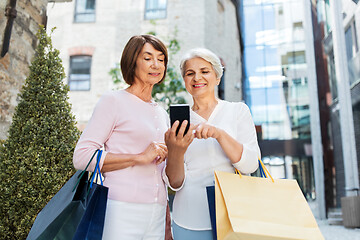 Image showing old women with shopping bags and cellphone in city