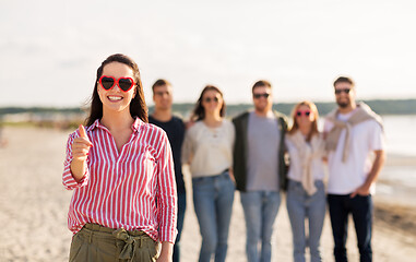 Image showing woman with friends on beach showing thumbs up