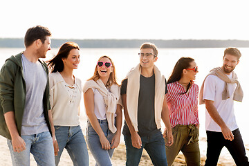 Image showing happy friends walking along summer beach