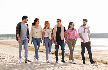 Image showing happy friends walking along summer beach