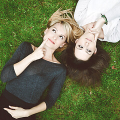 Image showing Two thoughtful girls lying in the grass