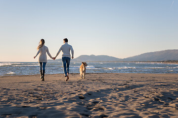 Image showing couple with dog having fun on beach on autmun day