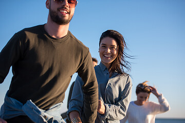 Image showing Group of friends running on beach during autumn day