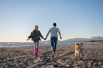 Image showing couple with dog having fun on beach on autmun day