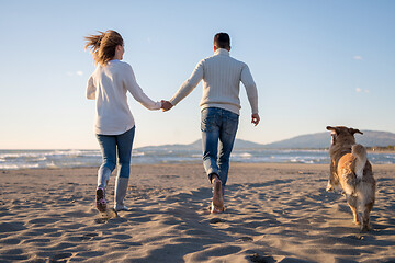 Image showing couple with dog having fun on beach on autmun day