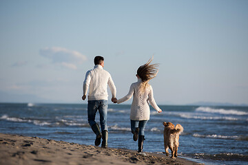 Image showing couple with dog having fun on beach on autmun day