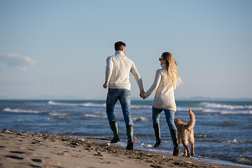 Image showing couple with dog having fun on beach on autmun day