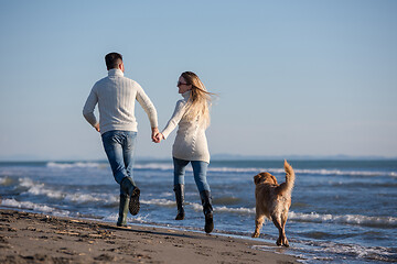 Image showing couple with dog having fun on beach on autmun day