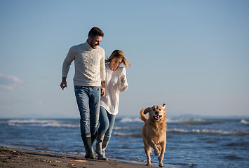 Image showing couple with dog having fun on beach on autmun day