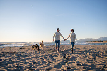 Image showing couple with dog having fun on beach on autmun day