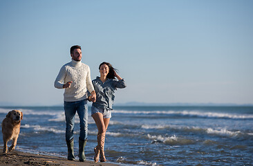 Image showing couple with dog having fun on beach on autmun day