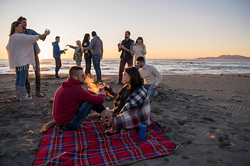 Image showing Couple enjoying with friends at sunset on the beach