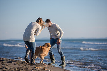 Image showing couple with dog having fun on beach on autmun day