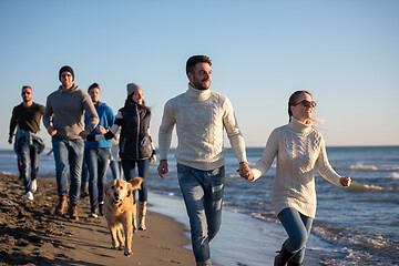 Image showing Group of friends running on beach during autumn day