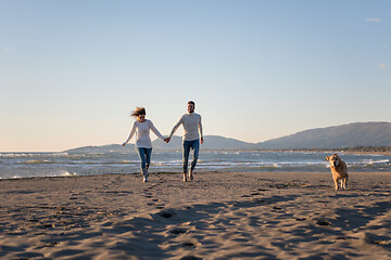 Image showing couple with dog having fun on beach on autmun day