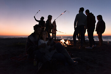 Image showing Couple enjoying bonfire with friends on beach