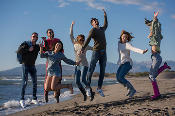 Image showing young friends jumping together at autumn beach