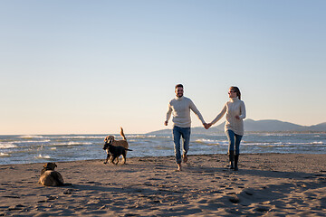 Image showing couple with dog having fun on beach on autmun day