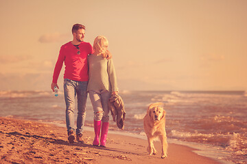 Image showing couple with dog having fun on beach on autmun day