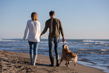 Image showing couple with dog having fun on beach on autmun day