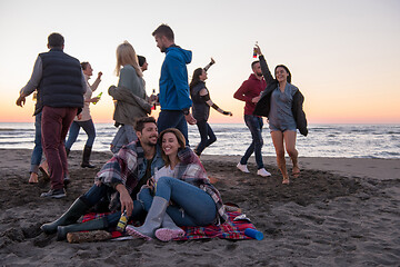 Image showing Couple enjoying with friends at sunset on the beach