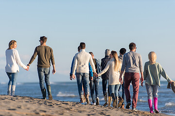 Image showing Group of friends running on beach during autumn day