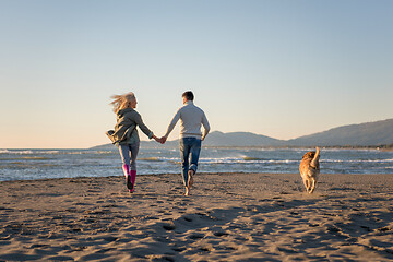 Image showing couple with dog having fun on beach on autmun day