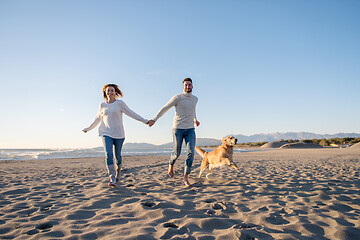 Image showing couple with dog having fun on beach on autmun day